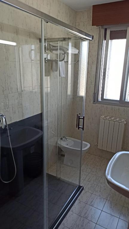 Mūsdienīga vannas istaba ar stūra dušu, tualeti un izsistajām logiem, kas nodrošina dabīgu apgaismojumu. Grīda ir flīzēta, radot elegantu izskatu.