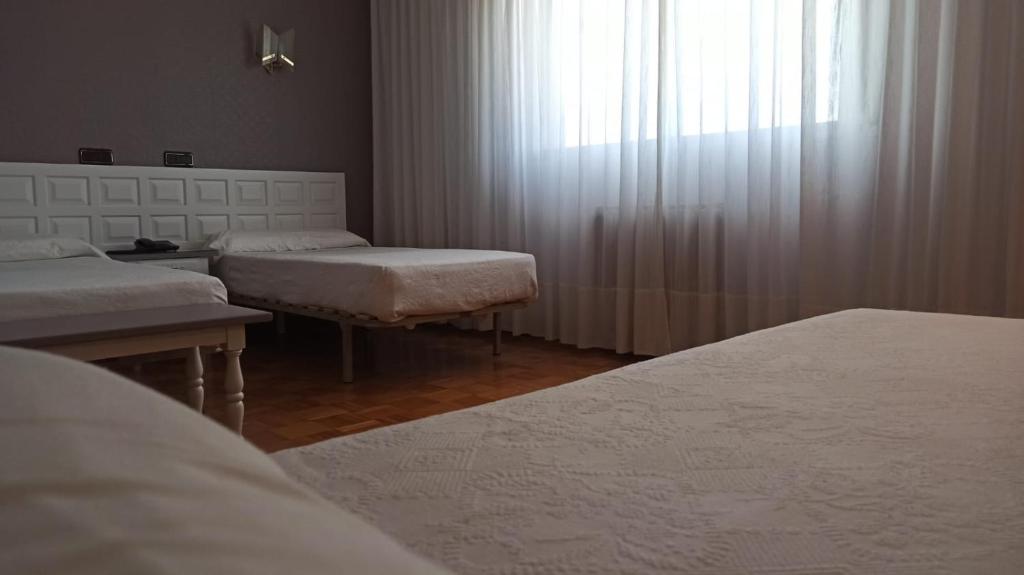 Gaismas un miera atmosfēra guļamistabā ar divām gultām un lielu logu, caur kuru ieplūst dabiska gaisma. Telpa ir iekārtota ar vienkāršu un elegantu dizainu.