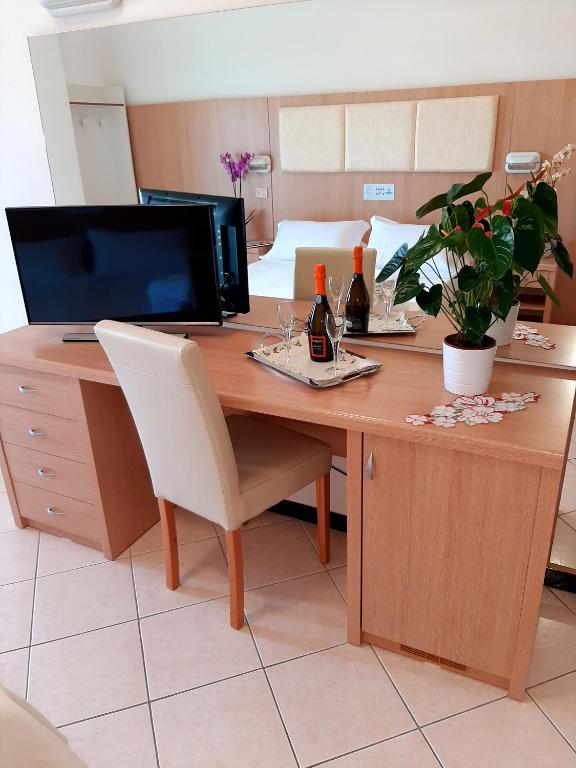 Mūsdienīgs viesnīcas numura rakstāmgalds ar televizoru, šampanieša pudelēm un glāzēm, kā arī telpaugiem, radot patīkamu atmosfēru relaksācijai.