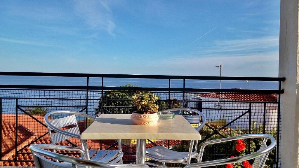 Skats uz jūru no balkona ar galdu un krēsliem, uz kura atrodas puķu pods. Ideāla vieta relaksācijai un baudīšanai.