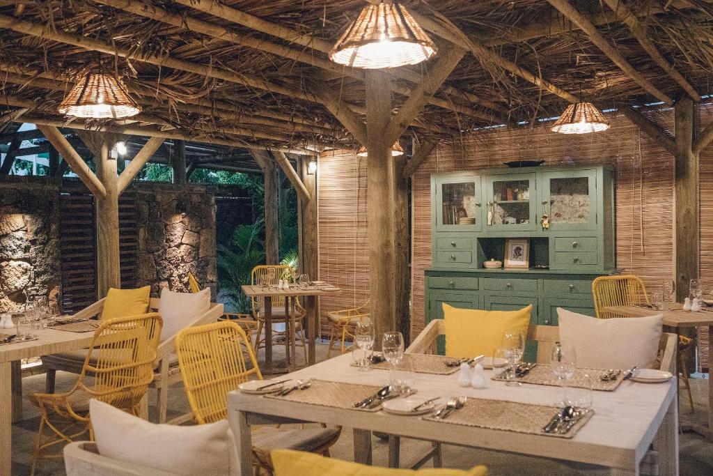 Restorāna interjers ar koka struktūru, rattan krēsliem un siltu apgaismojumu, radot mājīgu atmosfēru. Zaļā krāsā krāsota kumode pievērš uzmanību un papildina kopējo dizainu.