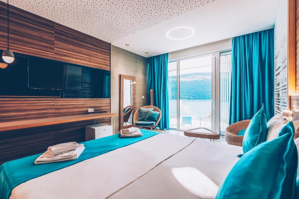 Mūsdienīgs viesnīcas numurs ar plašu gultu, zilu tekstilizstrādājumu un panorāmas logiem, kas piedāvā skatu uz dabu. Interjers ar koka elementiem un modernām mēbelēm rada relaksējošu atmosfēru.