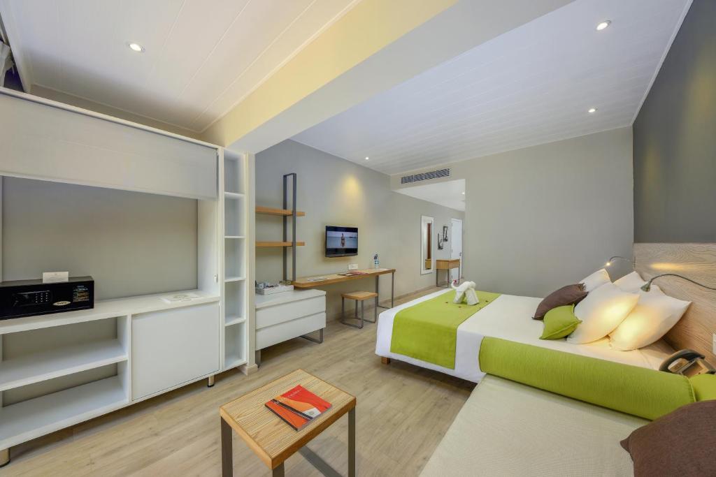 Mūsdienīgs viesnīcas numurs ar divām gultām, gaišu interjeru un koka grīdu. Numurā ir televizors, galds un uzglabāšanas plaukti.