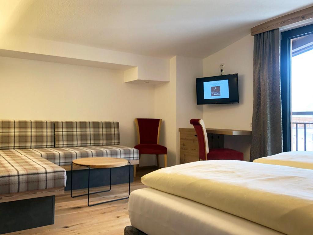 Mūsdienīga viesnīcas istaba ar divām gultām, dīvānu, televizoru un darba galdu. Interjers ir gaišs un ērts, ar koka grīdu un plašiem logiem.