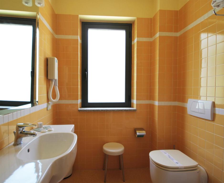 Rada Siri Hotel vannas istaba ar dzeltenām flīzēm un logu.