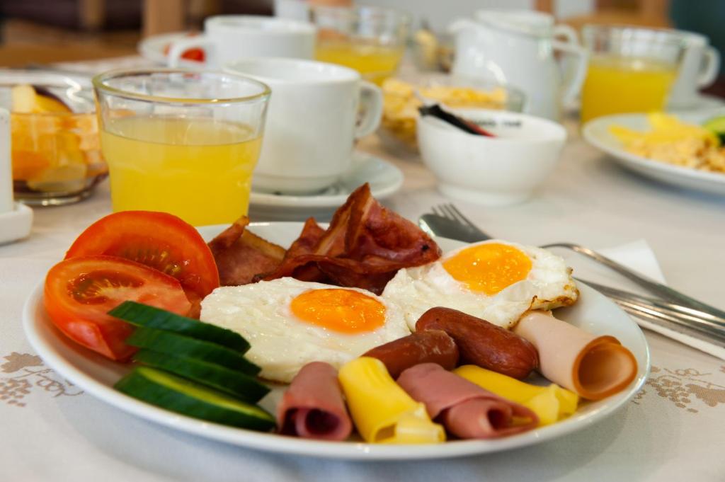 Sātīga brokastu plate ar ceptiem olu dzeltenumiem, speķi, desām, tomātiem un gurķiem, papildināta ar sulīgu apelsīnu sulu.