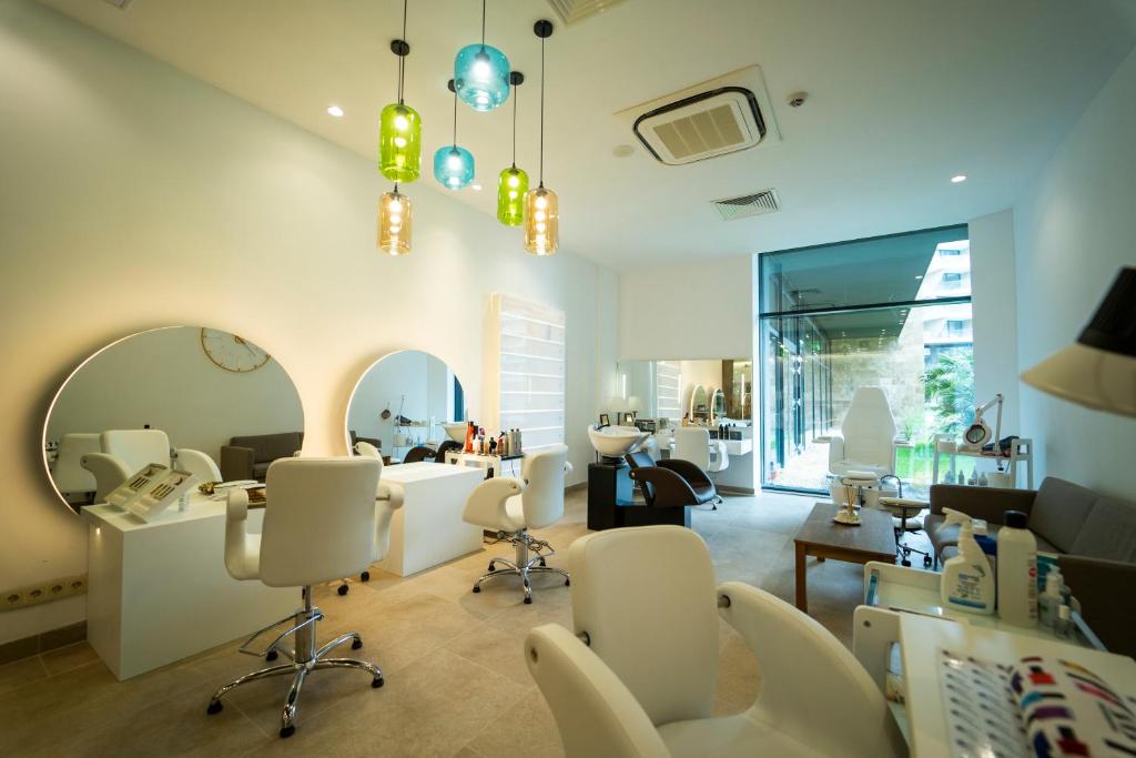 Mūsdienīgs frizētavas interjers ar gaismas ķermeņiem, elegantiem spoguļiem un komfortablām krēslām. Telpa ir gaiša un plaša, ar skatu uz dārzu.
