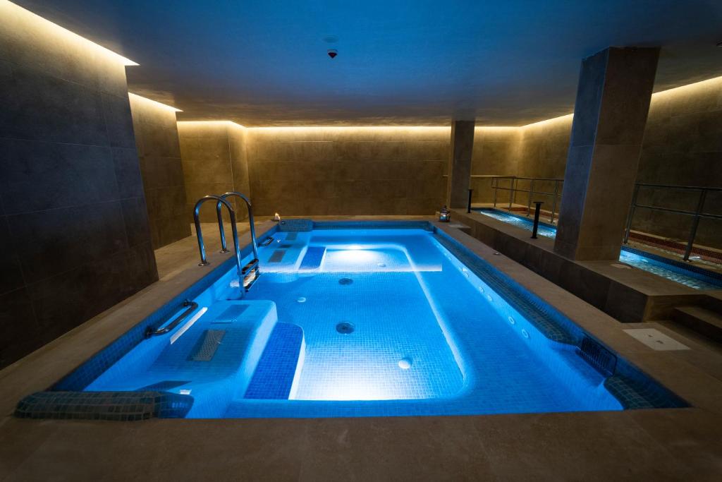 Mūsdienīgs spa ar apgaismotu baseinu, kas izceļas ar mierīgu atmosfēru un relaksējošu dizainu.