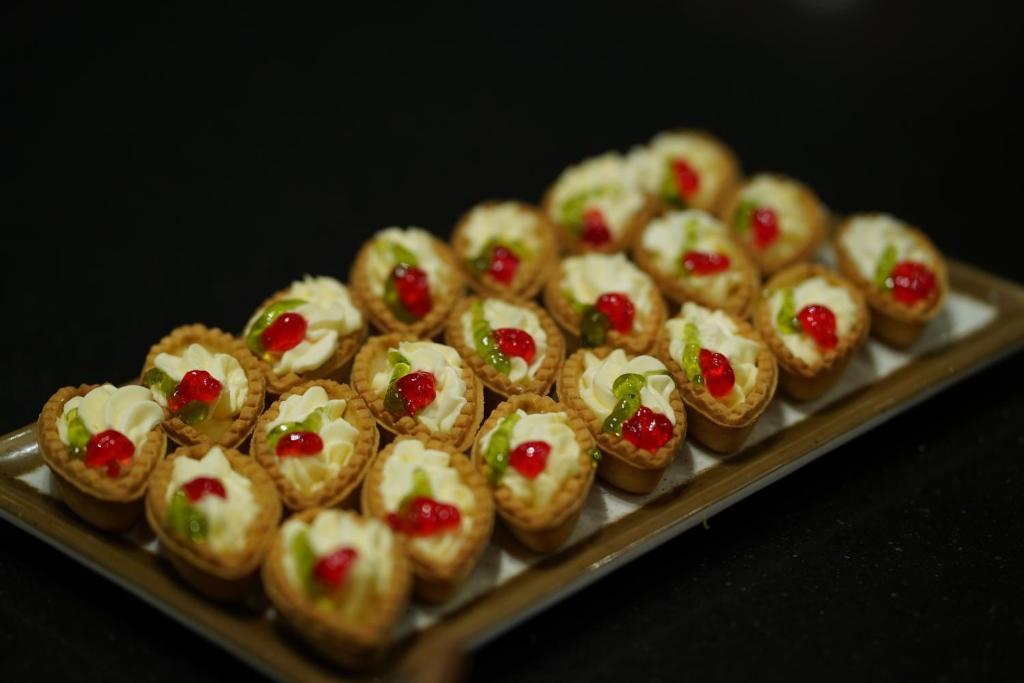 Saldējumus ar krēmveida pildījumu, rotātu ar ķiršiem un zaļām dekorācijām, pasniegti uz metāla paplātes.