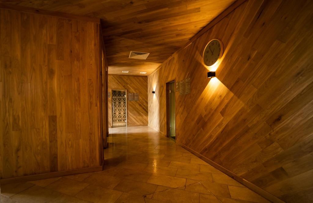 Koka apdare un siltas apgaismojums veido mājīgu un elegantu gaiteņa atmosfēru. Redzamas sienas ir izgatavotas no koka, piešķirot telpai dabīgu un modernu izskatu.