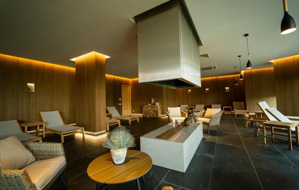 Mūsdienīgs spa atpūtas telpa ar komfortablām atpūtas krēsliem, dabīgiem materiāliem un mīkstu apgaismojumu. Telpā ir centrālais kamīns un elegants dekors, radot relaksējošu atmosfēru.