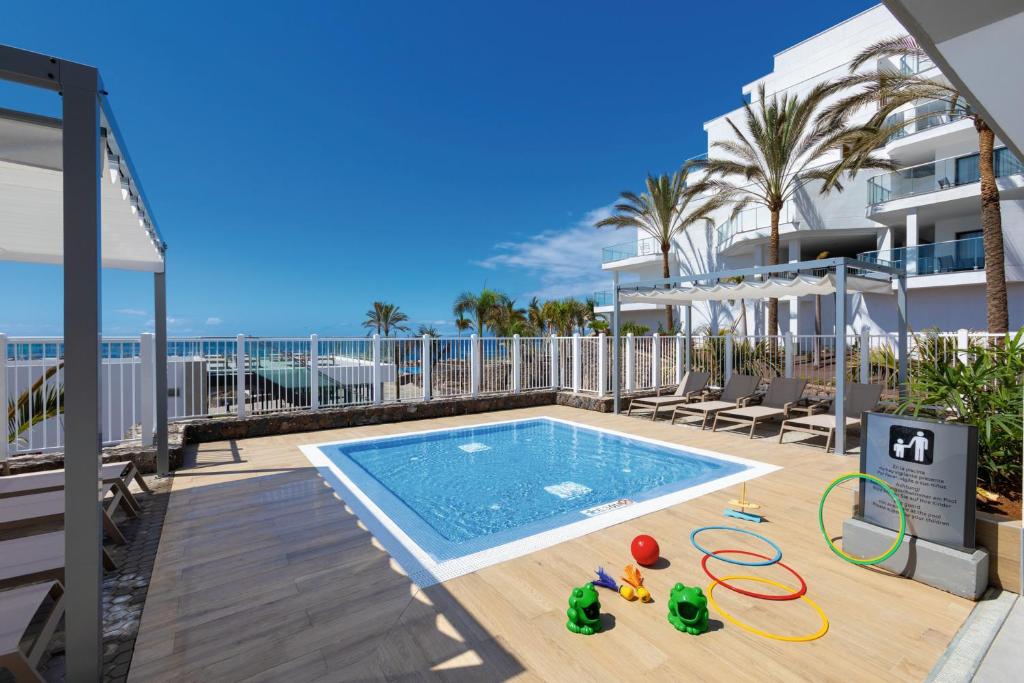 Baseins ar bērnu rotaļlietām, apkārt palmām un moderna dzīvojamā ēka, skats uz jūru. Perfect for family vacations.