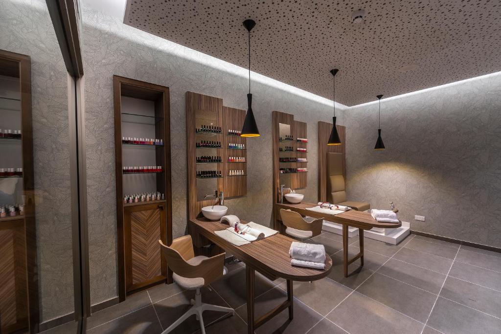 Mūsdienīgs manikīra salons ar elegantiem koka elementiem, gaismas lampām un plašu nagu lakas izvēli. Telpa ir gaiša un gaumīgi iekārtota, radot relaksējošu atmosfēru.