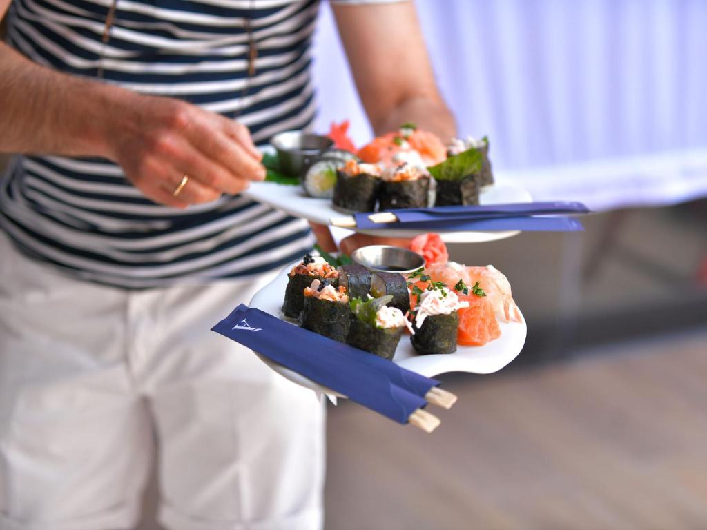 Sushi šķīvji ar dažādiem suši un garnelēm, ko pasniedz ar koka pārtikas nūjiņām. Ideāla izvēle gardēžiem, kuri novērtē japāņu virtuvi.
