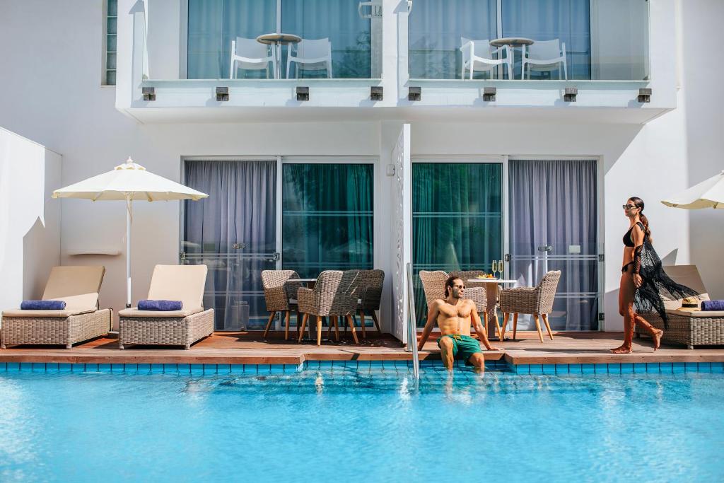 Peldbaseins ar saules gultām un ērtām sēdvietām, kur pāris atpūšas un izbauda brīvdienu atmosfēru.