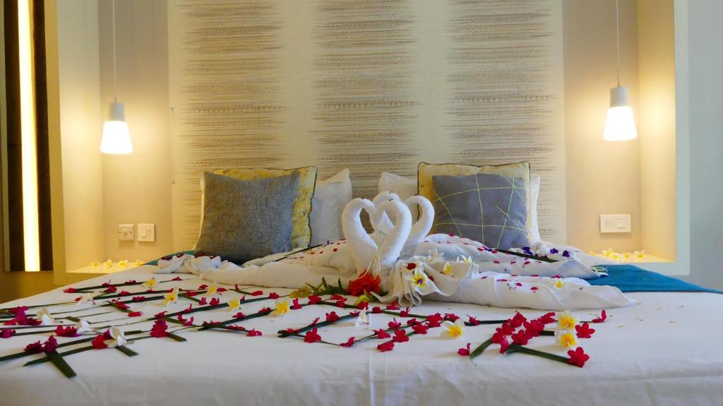 Romantiska gultnes gulta ar dekoratīvām gultas segām un ziedu rotājumiem, kas izveidoti sirds formā. Gaismas piekari un mūsdienīgs interjers rada mājīgu atmosfēru.