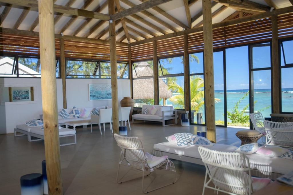 Mūsdienīgs atpūtas telpa ar lieliem logiem, kas piedāvā skatu uz jūru, un koka konstrukcijām. Telpā ir ērti dīvāni un krēsli, kas aicina atpūsties.