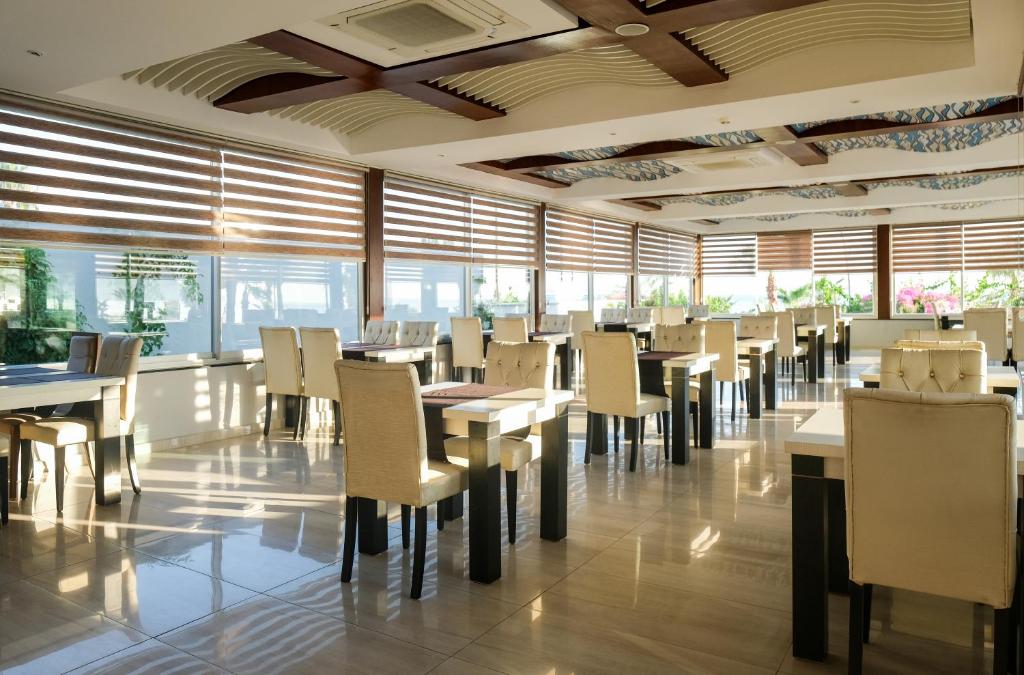 Mūsdienīgs restorāns ar elegantiem galdiem un krēsliem, kas ieplūst dabiska gaisma caur logiem. Interjers veidots ar koka un modernām detaļām, radot patīkamu atmosfēru.