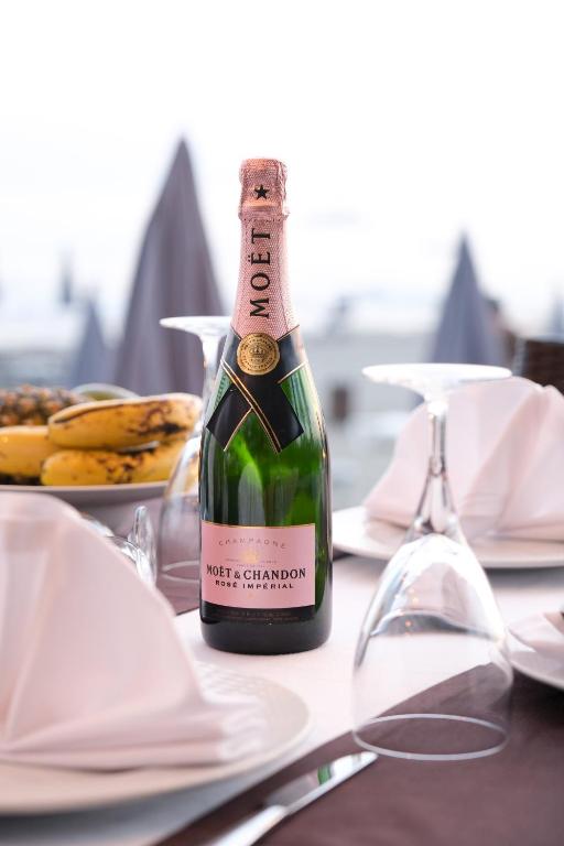 Šampanieša pudele Moët & Chandon Rosé Impérial, novietota uz eleganta galda ar salvetēm un glāzēm, papildināta ar augļu šķīvi.