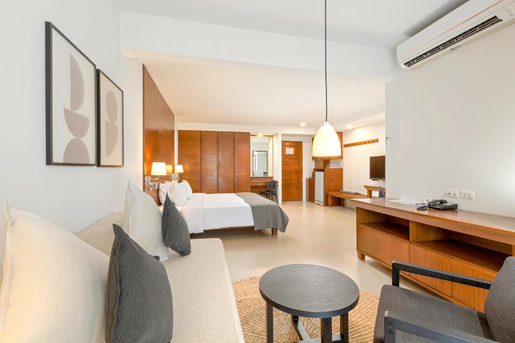 Mūsdienīga viesnīcas numura iekārtojums ar komfortablu dīvānu, galdu un televizoru, kā arī mākslinieciskām gleznām uz sienām. Telpa ir gaiša un plaša, radot relaksējošu atmosfēru.