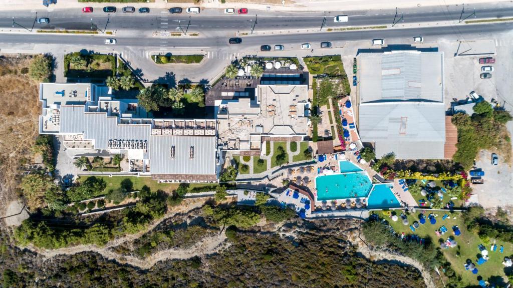 Apskatāma viesnīca ar baseinu un atpūtas zonām, kas izvietota pie jūras, ar blakus esošu ceļu un autostāvvietu.