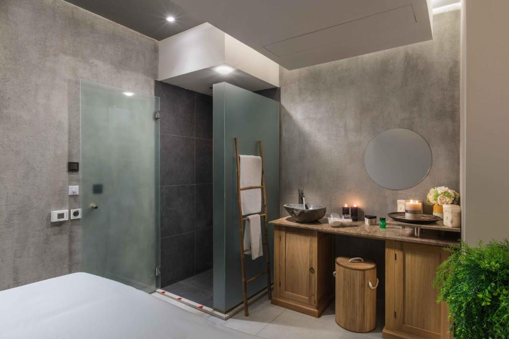 Moderna vannas istaba ar stikla dušas kabīni, koka mēbelēm un elegantiem dekoratīviem elementiem. Telpa apgaismota ar siltu gaismu, kas rada patīkamu atmosfēru.