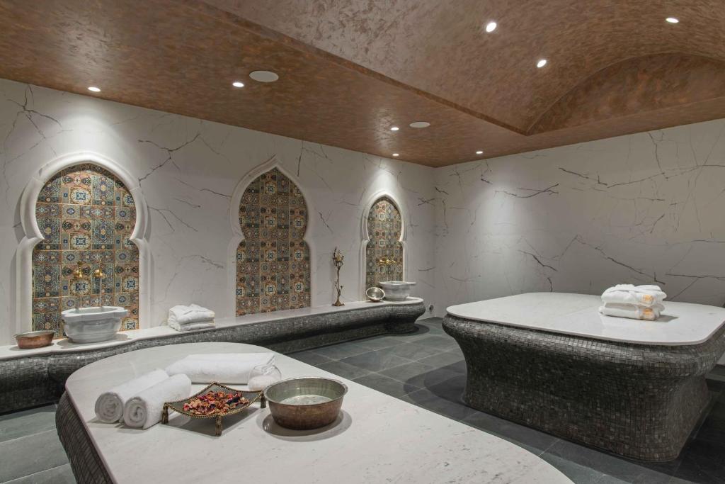 Elegants spa interjers ar mozaīkas elementiem un relaksējošu atmosfēru, kas ietver masāžas galdu un rotājumus. Ideāls vieta atpūtai un labsajūtai.