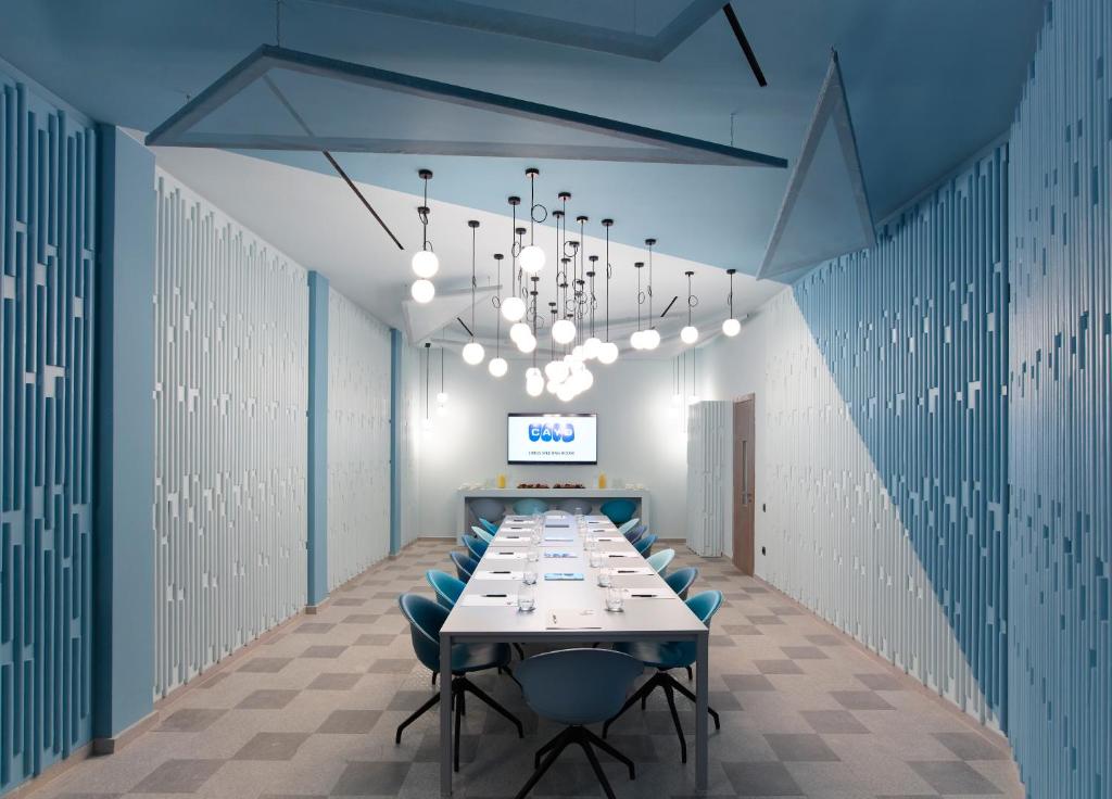 Mūsdienīga sanāksmju telpa ar gaiši zilu interjeru, ilgi galdi un stilīgas lampas, kas piešķir radošu atmosfēru. Ideāla vieta biznesa sanāksmēm vai prezentācijām.