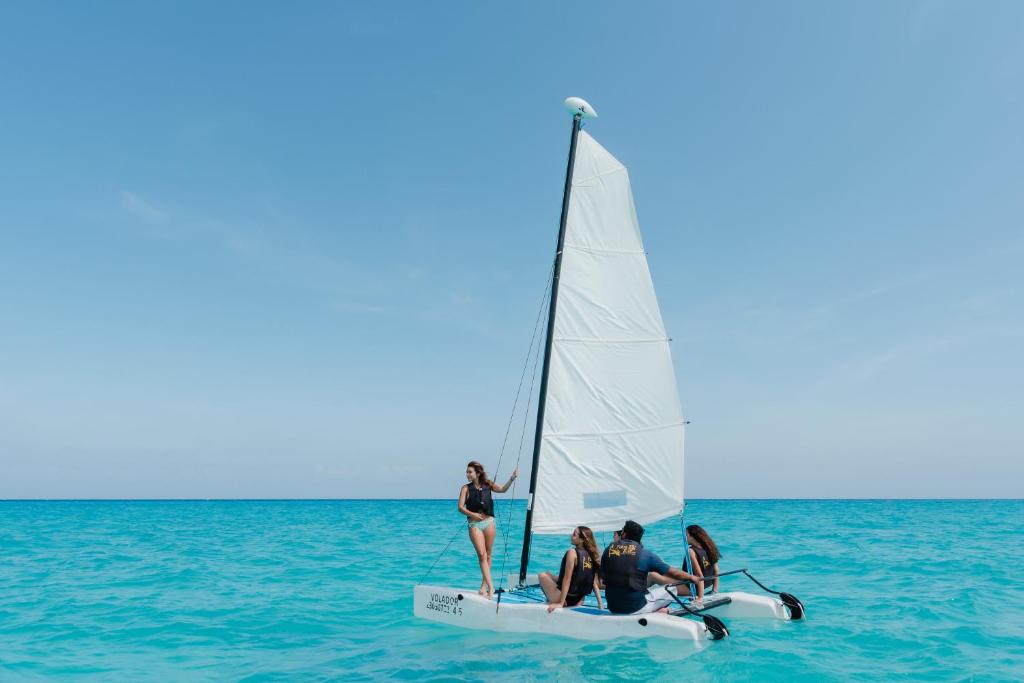Jahtā braucošas personas uz zilām jūrām, baudot saulainu laiku un mierīgu atmosfēru.