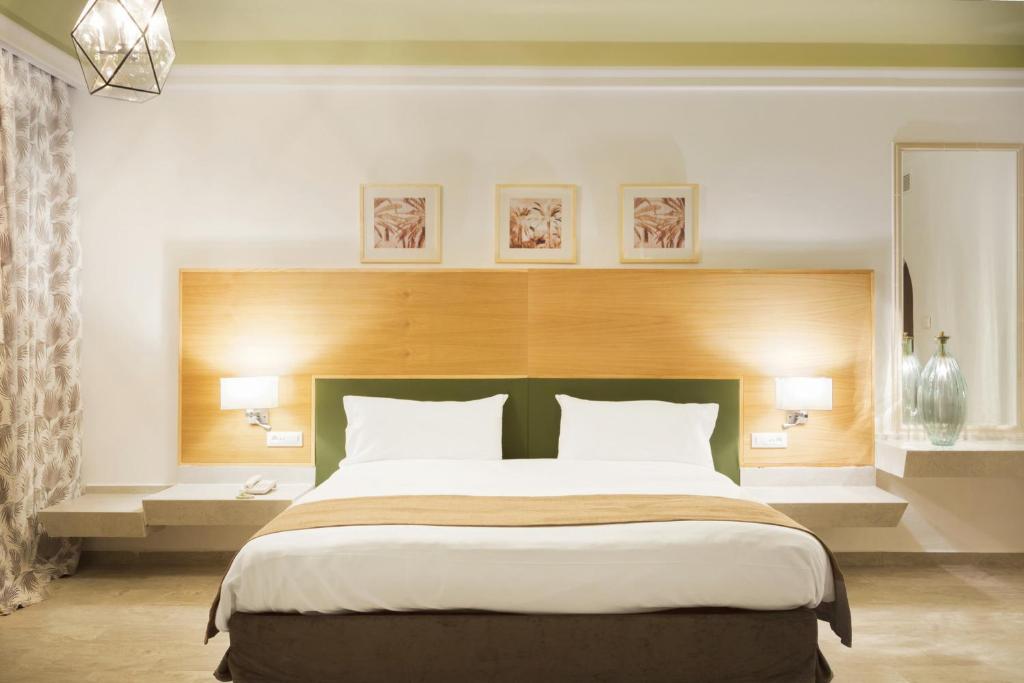 Mūsdienīga viesnīcas guļamistaba ar divguļamo gultu, koka apdari un dekoratīvām gleznām uz sienām. Interjerā ir neitrālu toņu palete un eleganti apgaismojuma elementi.