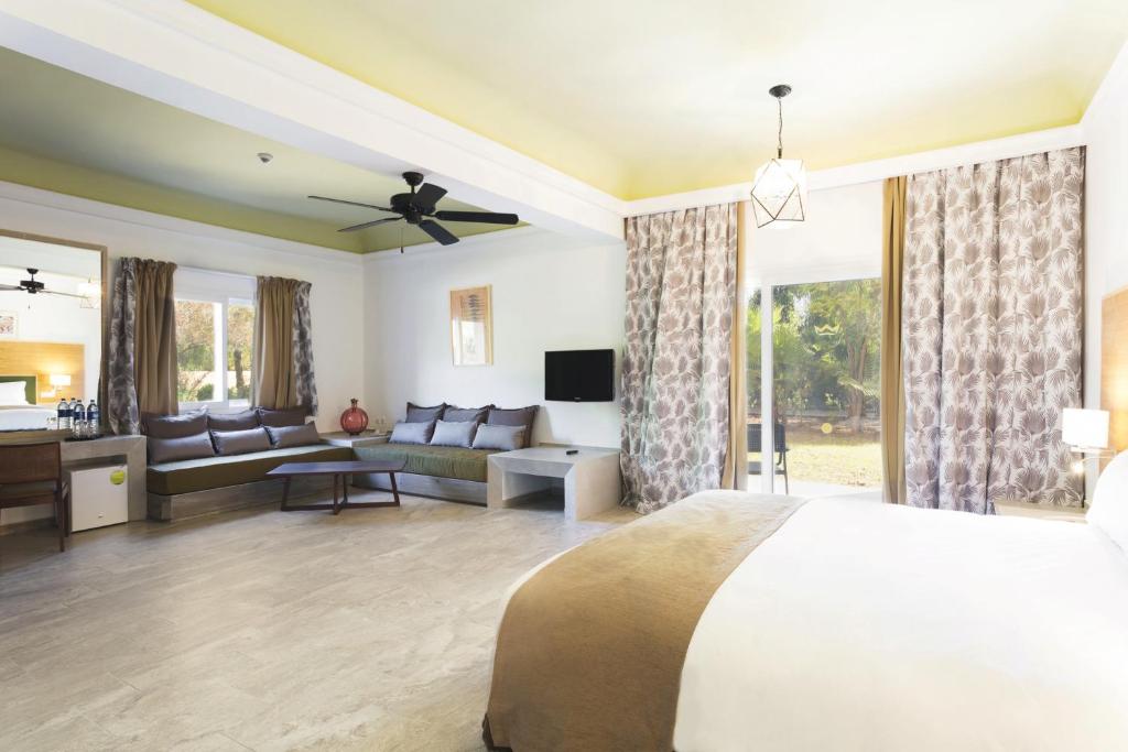 Mūsdienīgs viesnīcas numurs ar plašu telpu, ērtu dīvānu un lieliem logiem, kas nodrošina dabisko apgaismojumu. Interjērā ir gaišas krāsas un mūsdienīgs dizains, radot relaksējošu atmosfēru.