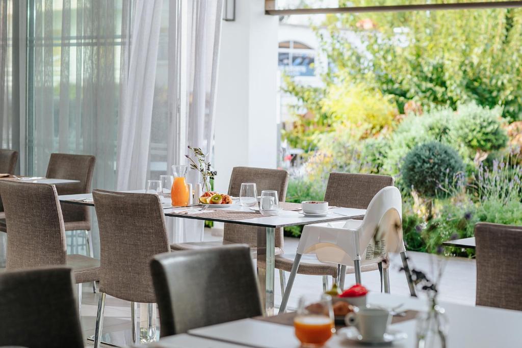 Mūsdienīgs restorāna interjers ar elegantām galdām un krēsliem, kas piedāvā gardu brokastu klāstu un skatu uz dārzu. Ideāla vieta relaksējošai maltītei.