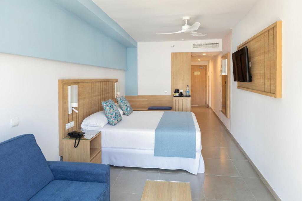 Mūsdienīga viesnīcas numura iekārtojums ar divguļamo gultu, dīvānu un televizoru. Numurā ir gaišas krāsas un komfortablas mēbeles.