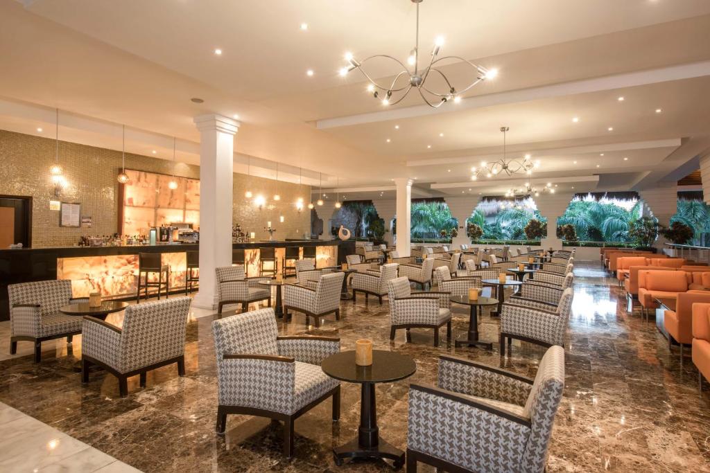 Elegants un plašs viesnīcas bārs ar modernu interjeru, kurā ir ērti sēžamie krēsli un stilīgi galdi. Gaismas elementi rada patīkamu atmosfēru, savukārt logi piedāvā skatu uz zaļajiem apstādījumiem.