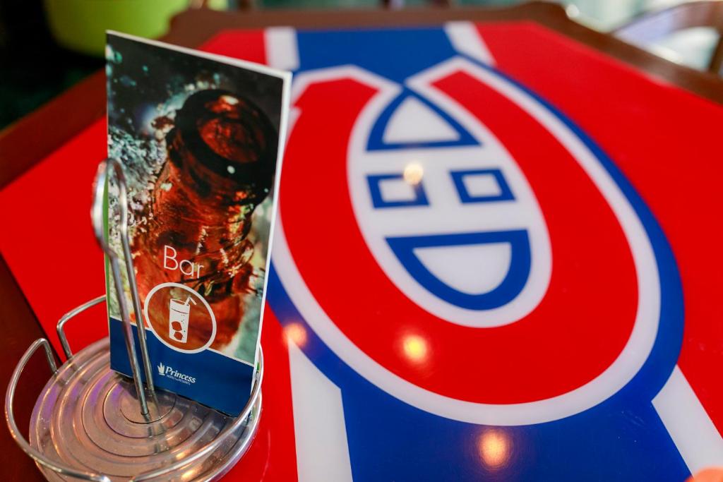 Bāra piedāvājuma buklets uz galda ar Habs logo, kas ir spilgti sarkans un zils.