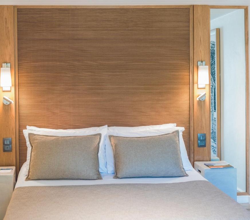 Mūsdienīgs guļamistabas interjers ar koka akcentiem, divām spilveniem un siltu apgaismojumu. Eleganta un relaksējoša atmosfēra.