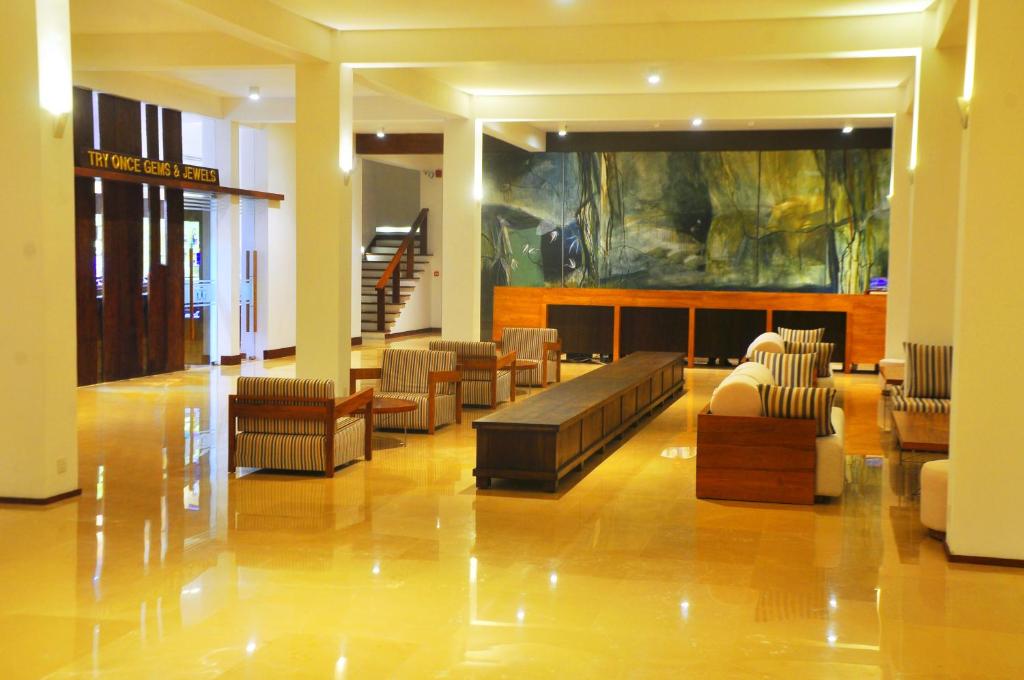 Mūsdienīga viesnīcas recepcija ar plašu telpu un elegantu interjeru. Vairāki sēdekļi un liels galds, kas izveidots relaksējošai atmosfērai.