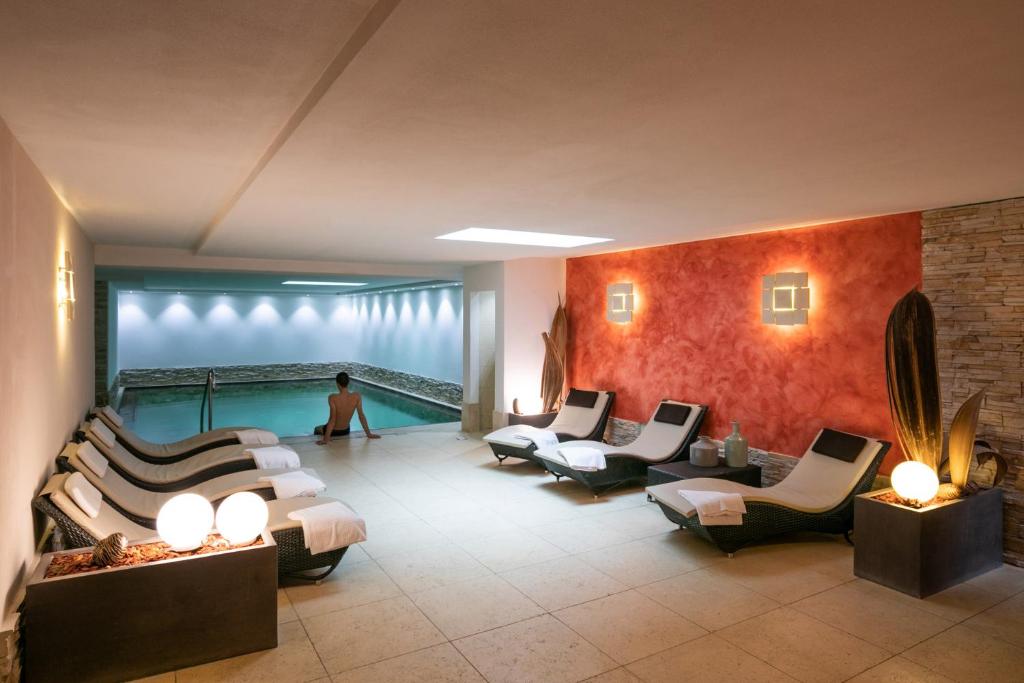 Mūsdienīga iekštelpu spa zona ar peldbaseinu un atpūtas krēsliem, radot relaksējošu atmosfēru. Siltas krāsas un apgaismojums piešķir telpai mierīgu noskaņu.