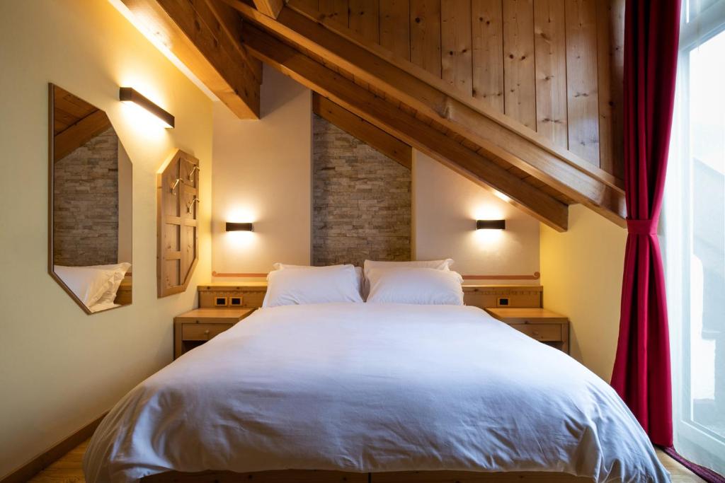 Mierīga guļamistaba ar koka apdari, divguļamo gultu un modernu apgaismojumu. Telpa ir iekārtota ar spoguļiem un sarkanu aizkaru, radot siltu un viesmīlīgu atmosfēru.