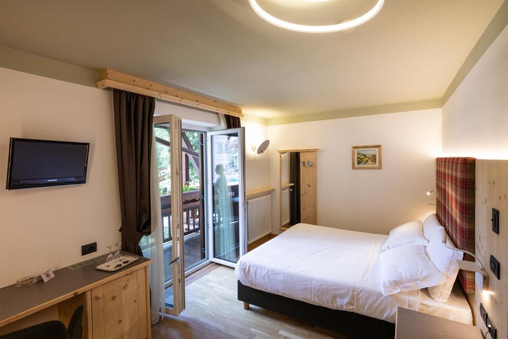 Mūsdienīgs viesnīcas numurs ar divguļamo gultu, televizoru un balkonu, kas piedāvā skatu uz dārzu. Interjerā ir koka elementi un silta apgaismojuma dizains.