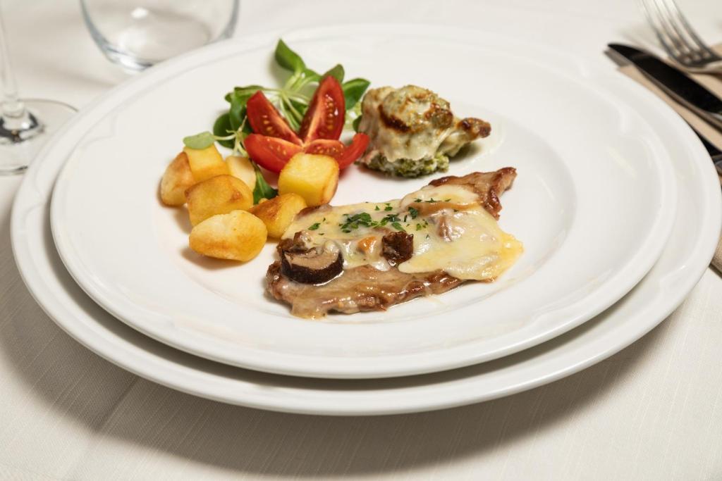 Gards ēdiens, kas sastāv no ceptas gaļas ar sieru, ceptiem kartupeļiem, dārzeņu salātiem un ceptiem dārzeņiem. Ideāla izvēle restorāna ēdienkartē.