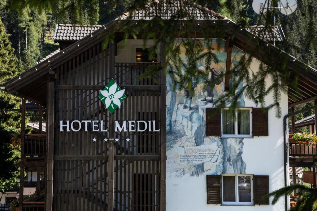 Viesnīcas "Hotel Medil" eksterjers ar dekoratīvu gleznu uz sienas un zaļajiem kokiem apkārt.