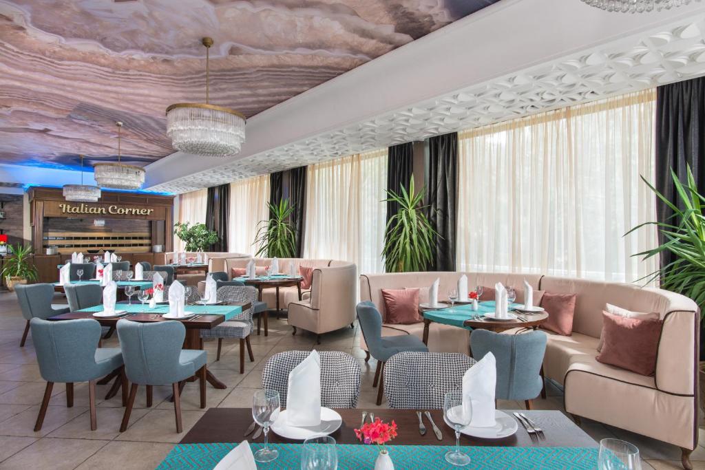 Mūsdienīgs restorāns ar elegantām mēbelēm, gaišām aizkariem un izsmalcinātu interjeru, radot patīkamu atmosfēru. Galdi ir klāti ar košām galdautām un dekoratīviem elementiem, kas papildina telpas šarmu.