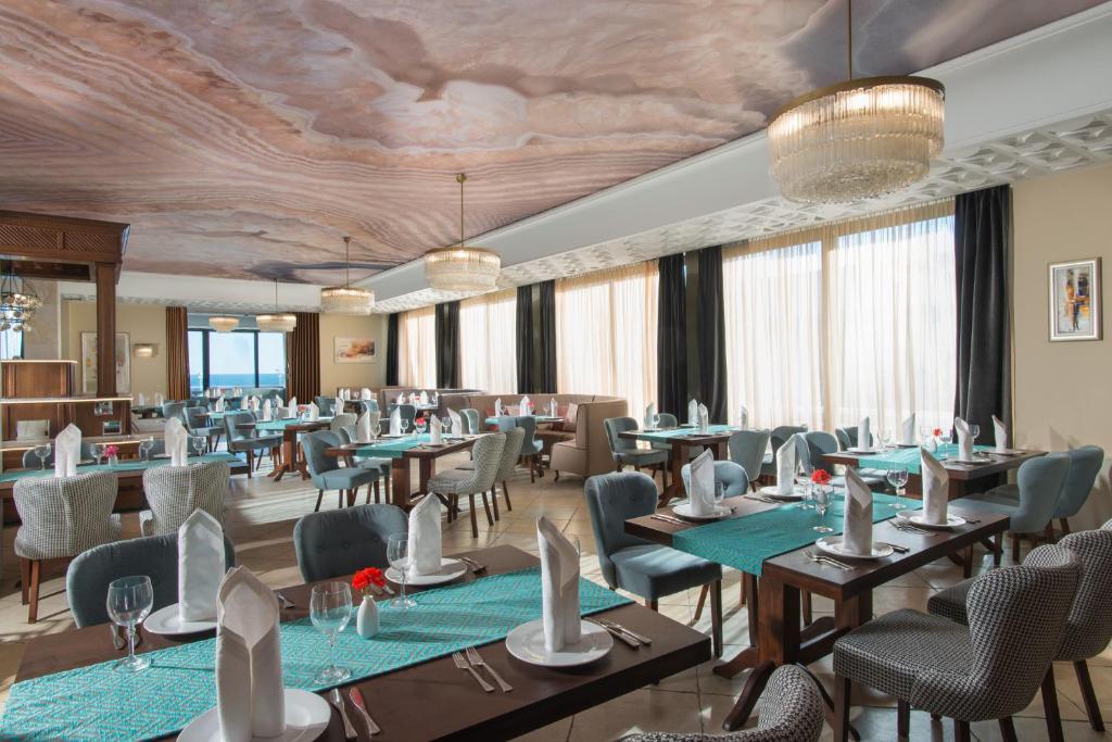 Elegants restorāns ar modernu interjeru, kas ietver krāšņu griestu dizainu un izsmalcinātas galda uzstādīšanas detaļas. Lieliskas skatu uz dabu un patīkama atmosfēra, ideāli piemērots pusdienām vai vakariņām.