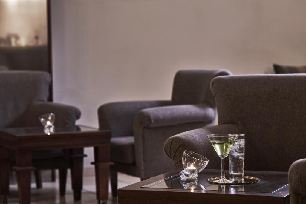 Mūsdienīgas viesnīcas interjers ar ērtām pelēkām krēslām un galdiņu, uz kura ir dzēriens un svece. Ideāla vieta relaksācijai un atpūtai.