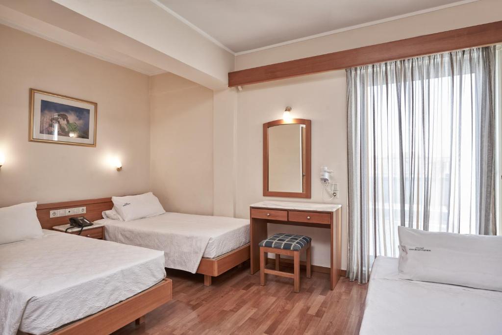 Gaiša viesnīcas numuriņa iekārtojums ar divām gultām, galdu un spoguli, kas nodrošina komfortu un mājīgumu. Liels logs ar aizkariem ļauj iekļūt dabīgajai gaismai.