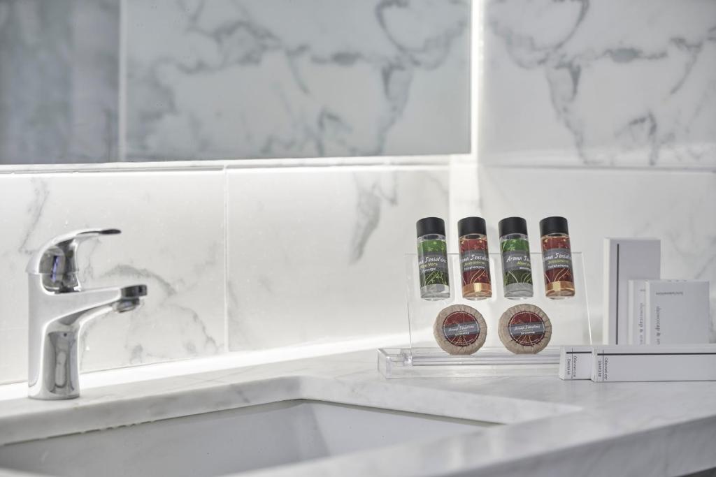 Marmora izstrādājums ar modernu izskatu, kurā redzams vannas istabas krāns un komplekts ar šampūnu un ķermeņa ziepēm. Elegants un stilīgs interjers.