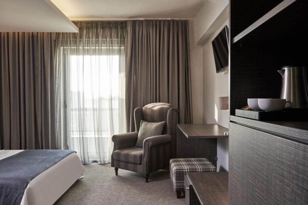 Mūsdienīgs viesnīcas numurs ar ērtu atpūtas krēslu, galdu un televizoru. Logi ar caurspīdīgu aizkaru nodrošina dabisko apgaismojumu.