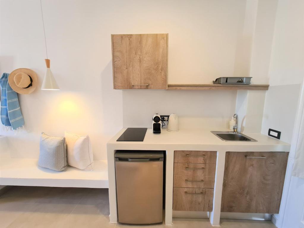 Mūsdienīga virtuve ar koka elementiem, iekārtota ar ledusskapi, kafijas automātu un trauku mazgājamo mašīnu. Telpai ir gaišas krāsas un ērti sēdvietas.