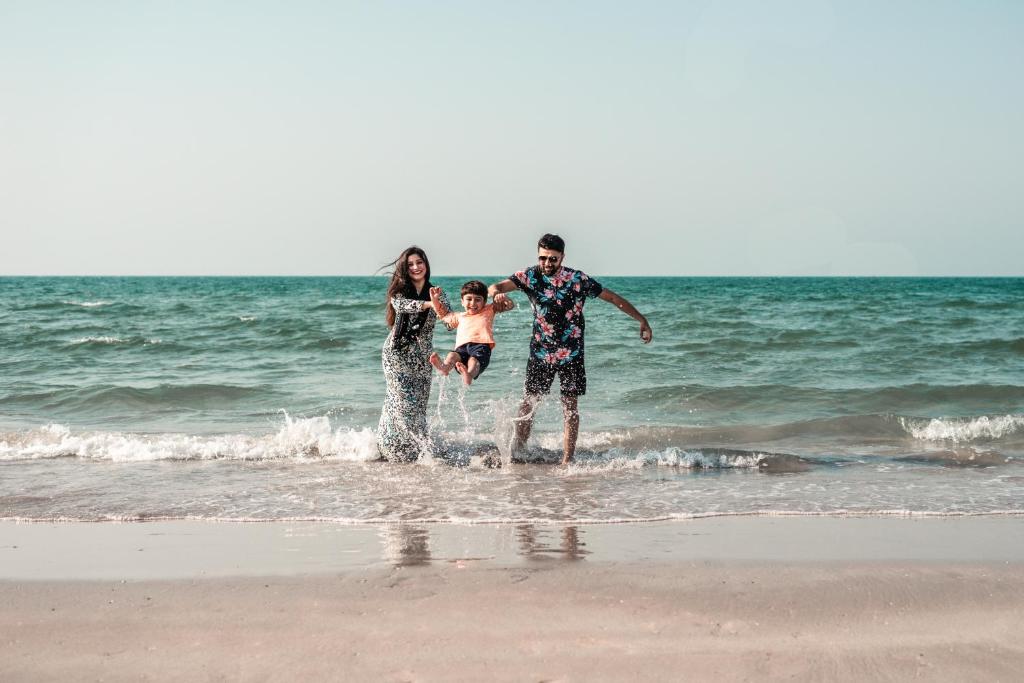 Ģimene pludmalē pie The Cove Rotana Resort piekrastē